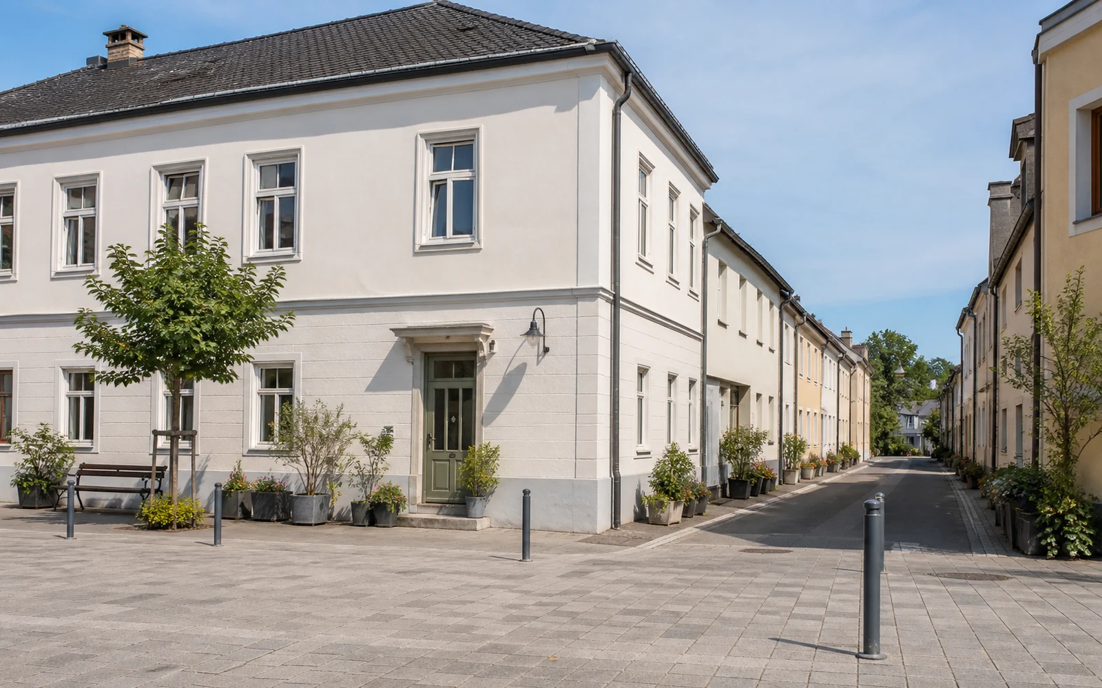 Helle Platzkante mit Wohngebäude und Übergang in eine ruhige zentrale Gasse